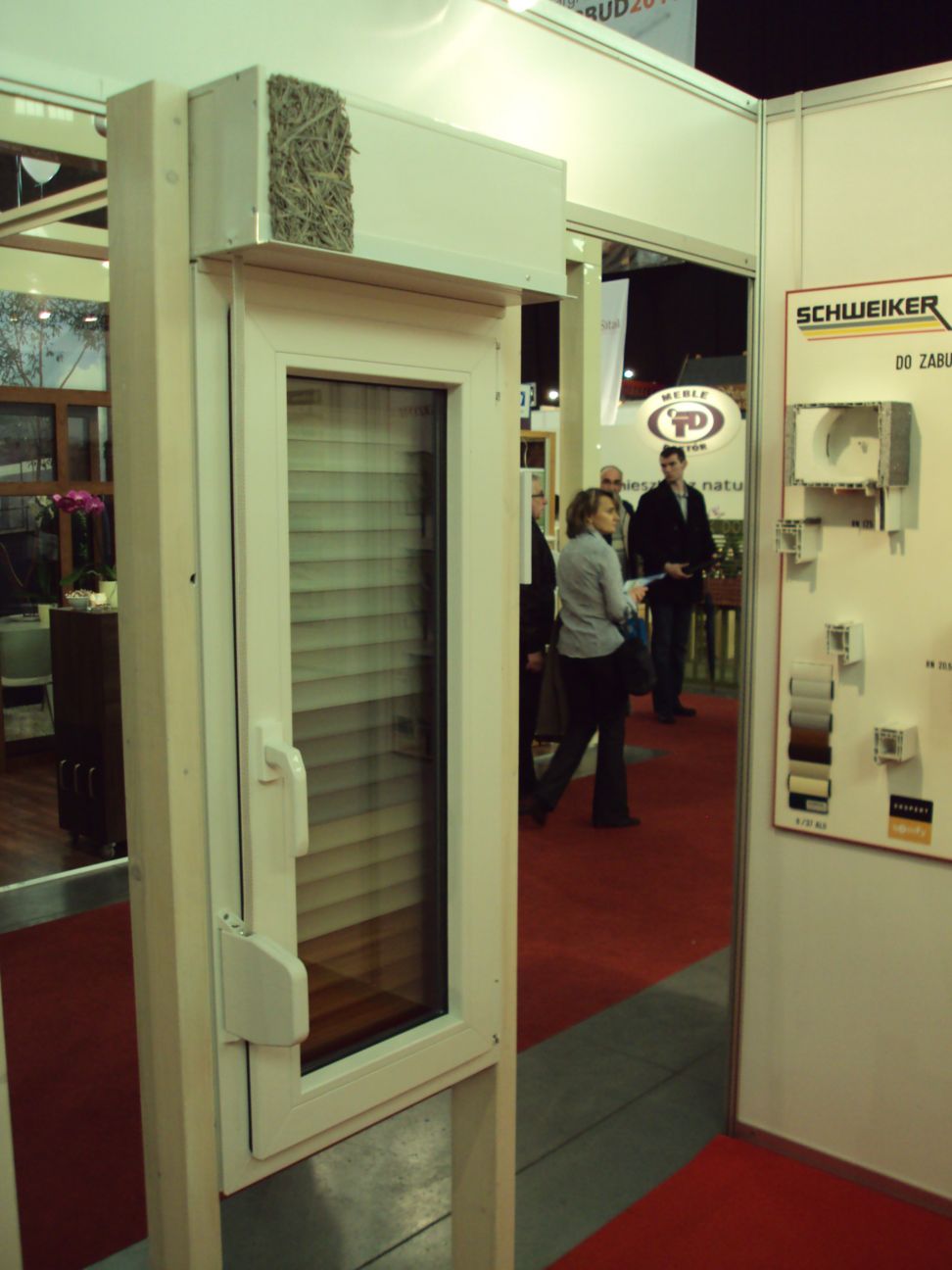 Ekspozycja okna z żaluzjami wewnętrznymi na stoisku targowym w Środzie Śląskiej, widoczny przekrój konstrukcji rolety z naturalnym wypełnieniem.